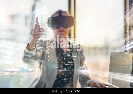 Die Zukunft des Geschäfts ist jetzt: Eine junge Geschäftsfrau, die ein Virtual-Reality-Headset bei der Arbeit trägt. Stockfoto