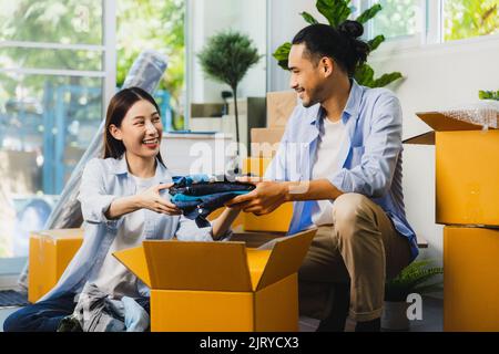 Liebe asiatische paar falten Tücher in Box oder nehmen Sie es aus, um Umzug neues Haus vorzubereiten Stockfoto
