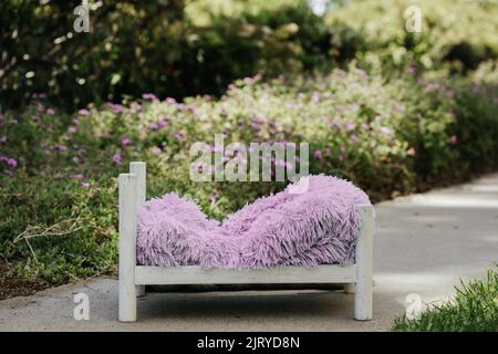 Sommer im Freien Neugeborenen Hintergrund - weißes Holzbett im grünen Garten mit rosa und lila Blume. Outdoor Garten Neugeborenen digitalen Hintergrund. Stockfoto