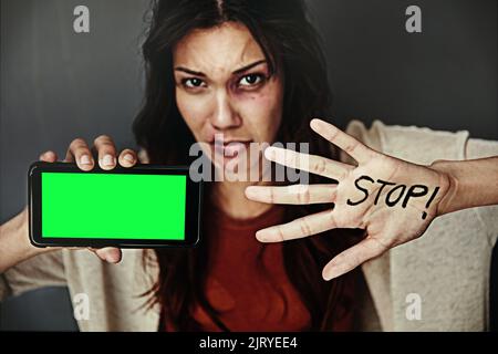 Hilf uns. Porträt einer gequetschten jungen Frau, die ein Mobiltelefon hält und das Wort AUF der Hand HÄLT. Stockfoto