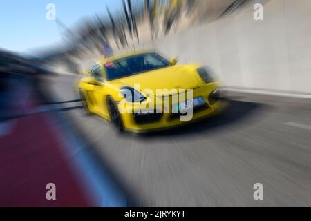 Dynamisches Foto mit Zoom-Effekt von Sportwagen-Rennwagen gelb Porsche Cayman GT4 Verlassen der Boxengasse, FIA Formel 1 Strecke, Circuit de Spa Stockfoto