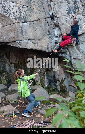 Ein Mann kletterte auf den Berg und eine Frau half ihm im Buky Canyon in der Nähe des Buky Dorfes im ukrainischen Cherkasy Oblast Stockfoto