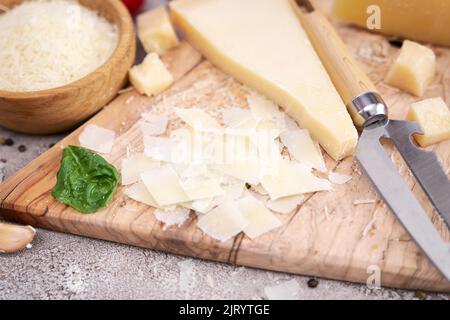 In Scheiben geschnittene Parmesan-Käseflocken auf einem hölzernen Schneidebrett in der heimischen Küche Stockfoto