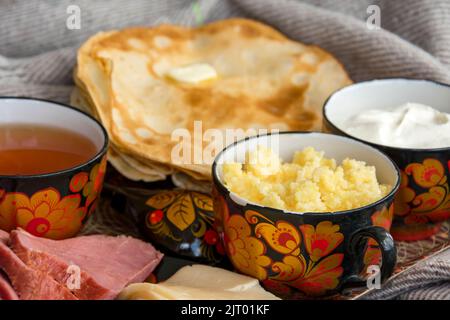 Frühstück im Bett für Ihre Liebsten, Pfannkuchen mit saurer Rahm, Käse und Fleisch, Maisbrei und eine Tasse frisch gebrühten Tee. Guten Morgen! Stockfoto