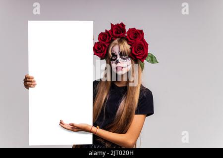 Teenager-Mädchen mit coolen Schädel Make-up mit Rosen auf dem Kopf Blick auf die Kamera im Studio Stockfoto