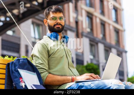 ein indischer Mann startet einen Geschäftsmann, der im Park sitzt und an einem Laptop arbeitet Stockfoto