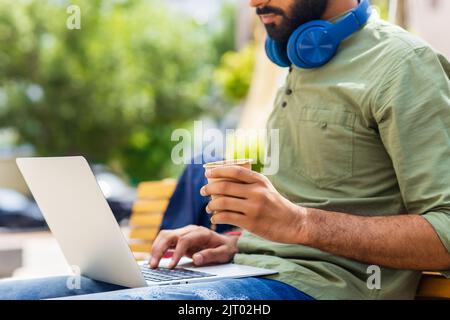 ein indischer Mann startet einen Geschäftsmann, der im Park sitzt und an einem Laptop arbeitet Stockfoto