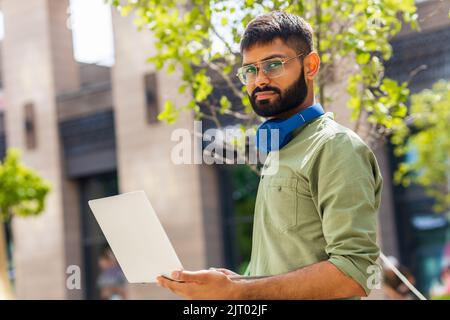 ein indischer Mann startet einen Geschäftsmann, der im Park sitzt und an einem Laptop arbeitet Stockfoto