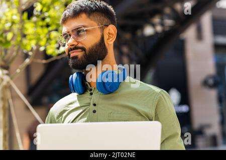ein indischer Mann startet einen Geschäftsmann, der im Park sitzt und an einem Laptop arbeitet Stockfoto