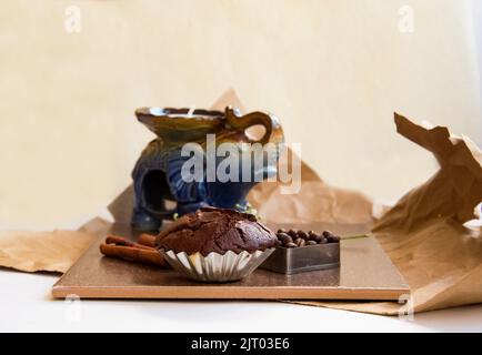 Weiße Kerze in Kerzenform, Elefantenform, Blütenzweig, Herzform Kaffeebohnen, Schokoladenmuffin, Zimtstangen, Kakao. Zusammensetzung in bro Stockfoto