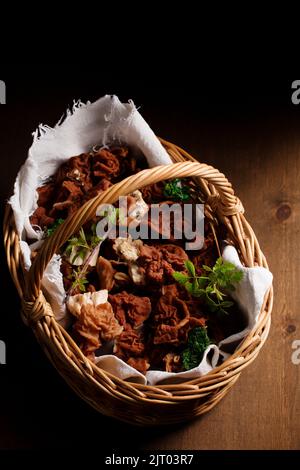 Waldmorellpilze in einem Korbkorb auf einem Holzhintergrund Stockfoto