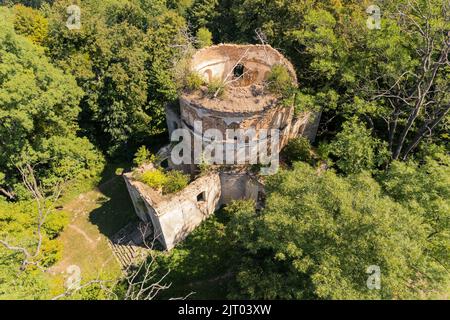 BirdsBlick auf das Äußere der beschädigten verlassenen Kirche mit Turm ohne Dach in der Mitte des grünen üppigen Waldes. Alte Tempelruinen. Horizontale Aufnahme. Hochwertige Fotos Stockfoto