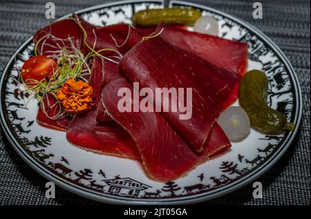 Getrocknetes Fleisch in Scheiben, eingelegte Gurken und Zwiebeln. Konzept für Vorspeisen. Traditionelle Schweizer Küche. Köstlich. Stockfoto