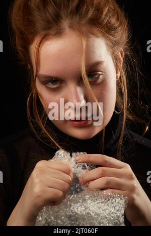 Gestresste Frau in Depression platzt Blasen der Verpackung Cellophan Stockfoto