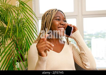 afroamerikanische Frau mit angenehmen Gespräch per Handy mit Freund Stockfoto