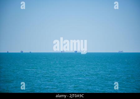 Viele riesige, kommerzielle Frachtschiffe warten darauf, den Hafen zu betreten. Stockfoto