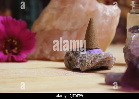 Amethyst-Kristalle mit Blumen und Räucherkegel auf Meditationsaltar Stockfoto