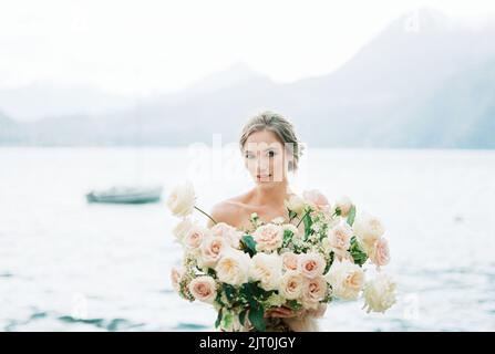 Braut mit einem Strauß Rosen am Strand. Hochformat Stockfoto