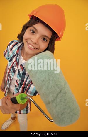 Maler in der Werkstatt. Renovierung und Reparatur. Teen Mädchen im Helm mit Pinsel malen. Kind in Hut. Kinderbaumeister Maler auf Baustelle. Stockfoto