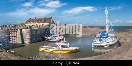 An einem schönen Tag im August genießen die Menschen die Sonne in Porlock Weir, während die einströmende Flut in den kleinen Hafen überflutet. Stockfoto