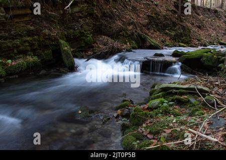 Das Wasser, das durch die Felsen im Flussbett von Kytserov fließt, erzeugt kleine Kaskaden um die Ufer, die mit bunten Herbstblättern bedeckt sind. Autu Stockfoto