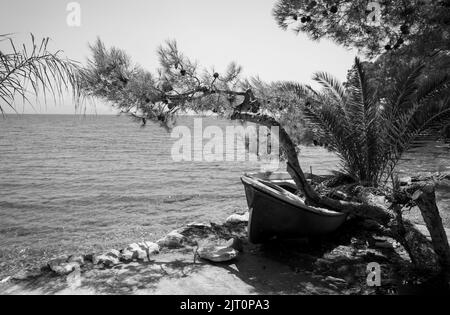 Verwittertes Fischerboot, das auf einem felsigen Strand auf Petalidi, Messinia, Griechenland liegt. Stockfoto