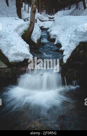 Atemberaubender Morgen am Fluss Recice in Masarykovo udoli in den Beskiden im Osten der Tschechischen republik. Wasserfall bricht durch den Schnee. Frostig Stockfoto