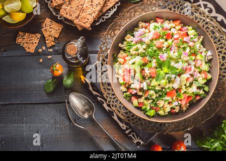 Arabische Küche; traditioneller mediterraner Salat „Tabbouleh“ oder „Tabouli“. Es ist ein frischer Kräuter- und Bulgur-Weizensalat mit Petersilie, Gurke und Tomate. Stockfoto
