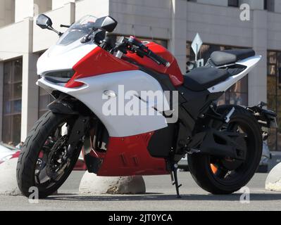 Rot-weißes italienisches Sportbike auf der Straße. Schönes Motorrad in den Farben weiß und orange auf der Straße geparkt Stockfoto