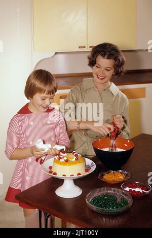 Backen Sie einen Kuchen in der 1950s. Eine Mutter und ihre Tochter in der Küche, die den Kuchen mit Sahnehahne fertig machen. Schweden 1958 Conard Ref. BV91-1 Stockfoto