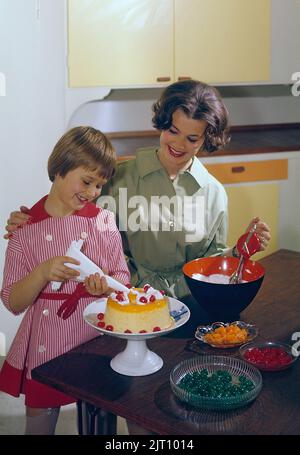 Backen Sie einen Kuchen in der 1950s. Eine Mutter und ihre Tochter in der Küche, die den Kuchen mit Sahnehahne fertig machen. Schweden 1958 Conard Ref. BV91-2 Stockfoto