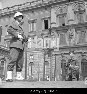 Fotograf im Jahr 1950s. Ein kleiner Junge mit seiner Kamera im Hof des königlichen Schlosses in Stockholm macht ein Bild des Burgwächters, der in Uniform und Waffe steht. Schweden 1951 Conard Ref. 2443 Stockfoto