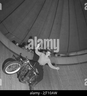 Motorradfahrer in der 1940s. A Ein junger Mann auf seinem Motorrad während einer Show in der Wall of Death (manchmal bekannt als Wall of Death, Motordrome, Silodrome. Wall of Death ist eine holzbeplankte tonnenförmige Arena, in der Zuschauer von oben beobachten, wie Motorräder oder andere motorisierte Fahrzeuge mit hoher Geschwindigkeit um sie herum fahren, oft andere Stunts durchführen. Schweden 1947 Conard Ref. 1103 Stockfoto