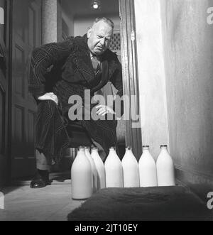 Mann der 1940s. Ein Mann war sichtlich enttäuscht über die verschiedenen Milchflaschen, die vor seiner Türschwelle standen. Er ist in der Stadtwohnung zurückgeblieben, während seine Frau und Familie einen Sommerurlaub machen. Vielleicht hat er in diesen Junggesellentagen mehr Bier als Milch genossen. Schweden 1942 Ref. C22-4 Stockfoto