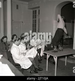 Kunstschule der 1940s. Eine Gruppe junger Männer und Frauen zeichnet das Bild des jungen Mannes, der vor ihnen auf einem Tisch steht und in einem dramatischen Herrenhaus posiert. Das männliche Modell ist in typischen 1940s Kleidern gekleidet. Möglicherweise ein Bild tacen während einer Kunstklasse. Schweden 1942 Kristoffersson Ref. A40-2 Stockfoto