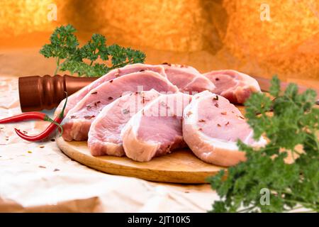 Frische rohe Schweinekoteletts auf einem Schneidebrett. Anordnung auf dem Geschenkpapier Stockfoto