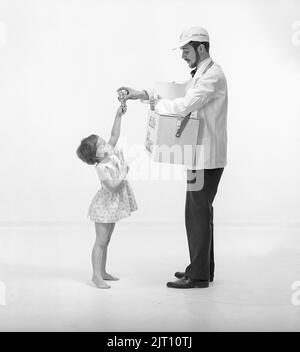 Eis in der 1960s. Ein Mädchen mit dem Eisverkäufer, das eine Kühlbox mit sich hat und ihr iice-Cream daraus geben lässt. Schweden 1960 Ref. CV12-11 Stockfoto