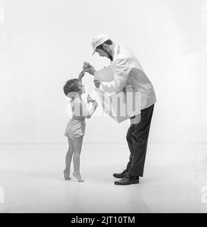 Eis in der 1960s. Ein Mädchen mit dem Eisverkäufer, das eine Kühlbox mit sich hat und ihr iice-Cream daraus geben lässt. Schweden 1960 Ref. CV12-12 Stockfoto