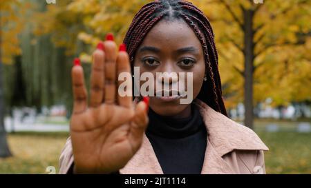 Nahaufnahme einer jungen, ernsthaft fokussierten, wütenden afroamerikanischen Frau, die eine Handfläche vor sich hält, mit einer Stop-Geste, die ein Verbotsschild mit verbotenem Schutz zeigt Stockfoto