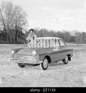 In der 1960s. Eine junge Frau im Winter mit ihrem brandneuen Auto, einem DKW Junior. Deutscher Automobilhersteller, der auch Motorräder herstellt, gehört zur Auto Union. Sie sieht glücklich aus und ist in warme Winterkleidung gekleidet. Schweden 1961. Stockfoto