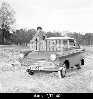 In der 1960s. Eine junge Frau im Winter mit ihrem brandneuen Auto, einem DKW Junior. Deutscher Automobilhersteller, der auch Motorräder herstellt, gehört zur Auto Union. Sie sieht glücklich aus und ist in warme Winterkleidung gekleidet. Schweden 1961. Stockfoto