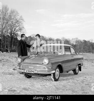 In der 1960s. Ein Paar im Winter mit ihrem brandneuen Auto, einem DKW Junior. Deutscher Automobilhersteller, der auch Motorräder herstellt, gehört zur Auto Union. Sie sehen glücklich aus und sind in warme Winterkleidung gekleidet. Schweden 1961. Stockfoto