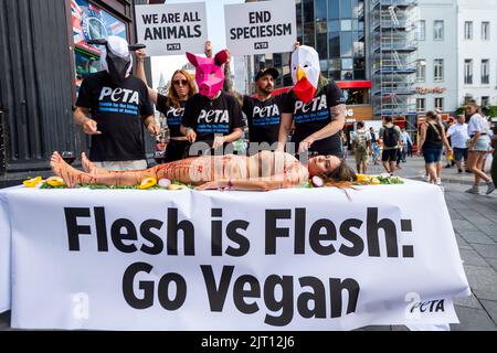 London, Großbritannien. 27. August 2022. Als Tiere gekleidete Demonstranten „speisen“ auf einem „blutverschmierten“ Menschen auf dem Leicester Square, um den „Welttag für das Ende des Speziesismus“ zu begehen. Das „Lunch-in“ ist Teil der Bemühungen von PETA (People for the Ethical Treatment of Animals), Speziesismus in Frage zu stellen und die Rechte der Tiere zu schützen. Kredit: Stephen Chung / EMPICS / Alamy Live Nachrichten Stockfoto