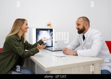 Erwachsene männliche orthopädische Arzt Beratung einer jungen weiblichen Patientin Stockfoto