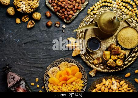 Ramadan-Konzept. Sorten von getrockneten Früchten, Nüssen, arabischem Kaffee, Datteln und traditioneller Ramadan-Laterne auf rustikalem dunklen Hintergrund. Stockfoto