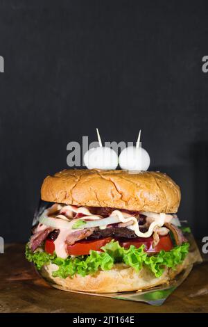 kolumbianischen Hamburger serviert auf einem Holzbrett mit einem schwarzen Hintergrund mit Platz, um Text zu kopieren. Street Food in kolumbien mit zwei Wachteleiern in der gemacht Stockfoto