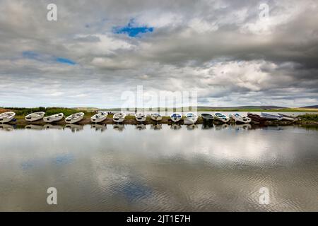 Loch Harray, Orkney, Großbritannien. 27. August 2022. Dinghies spiegeln sich in den ruhigen Gewässern von Loch Harray, Orkney Festland, Großbritannien. Die Boote werden von einheimischen Fliegenfischern genutzt. Kredit: Peter Lopeman/Alamy Live Nachrichten Stockfoto