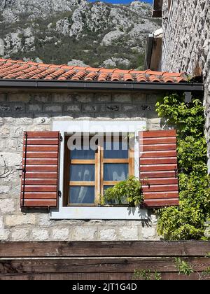 Holzfenster mit Fensterläden an der Steinfassade des Hauses Stockfoto