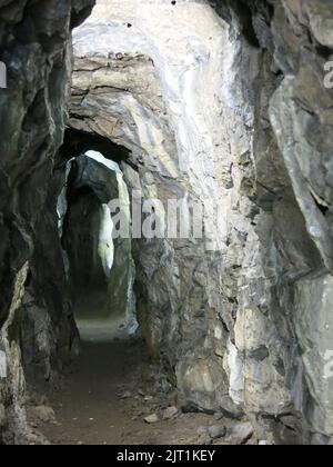 Blick in den Stollen oder den horizontalen Felstunnel, durch den Besucher in der Old Lead Mine, Cascades Gardens, Derbyshire, ein Stück weit laufen können. Stockfoto
