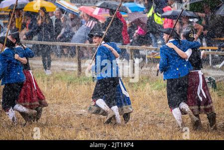 27. August 2022, Baden-Württemberg, Markgröningen: Bei starkem Regen führen die Teilnehmer des Markgröninger Schäferlaufs den Schäfer-Tanz auf einem Stoppelfeld auf. Foto: Christoph Schmidt/dpa Stockfoto